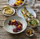 Mediterranean  food presented on plates and in bowls on a rustic wooden table