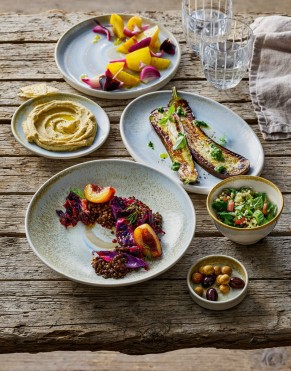 Mediterranean  food presented on plates and in bowls on a rustic wooden table