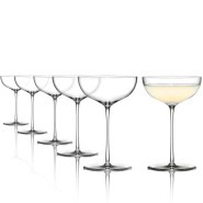 A set of elegant coupe cocktail glasses, featuring five empty glasses aligned in a row and one filled with a light-colored cocktail.
